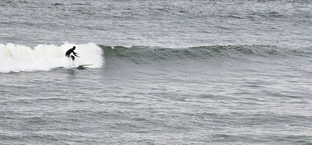 Surfer riding a shoulder high wave in front of the shop